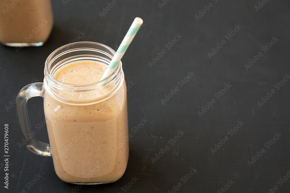 Healthy banana apple smoothie in glass jars over black background, low angle view. Space for text. Healthy banana apple smoothie in glass jars over black background, low angle view. Space for text.