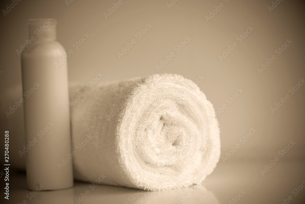 White delicate soft background of clean white close up towel rolled blanket textile and shampoo, soap, washcloth sepia toned White delicate soft background of clean white close up towel rolled blanket textile and shampoo, soap, washcloth sepia toned