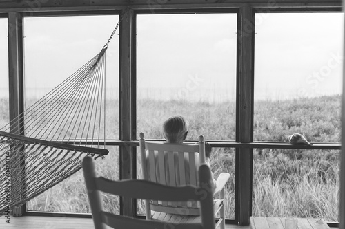 Black And White Photo Of Man Sitting On Back Porch 