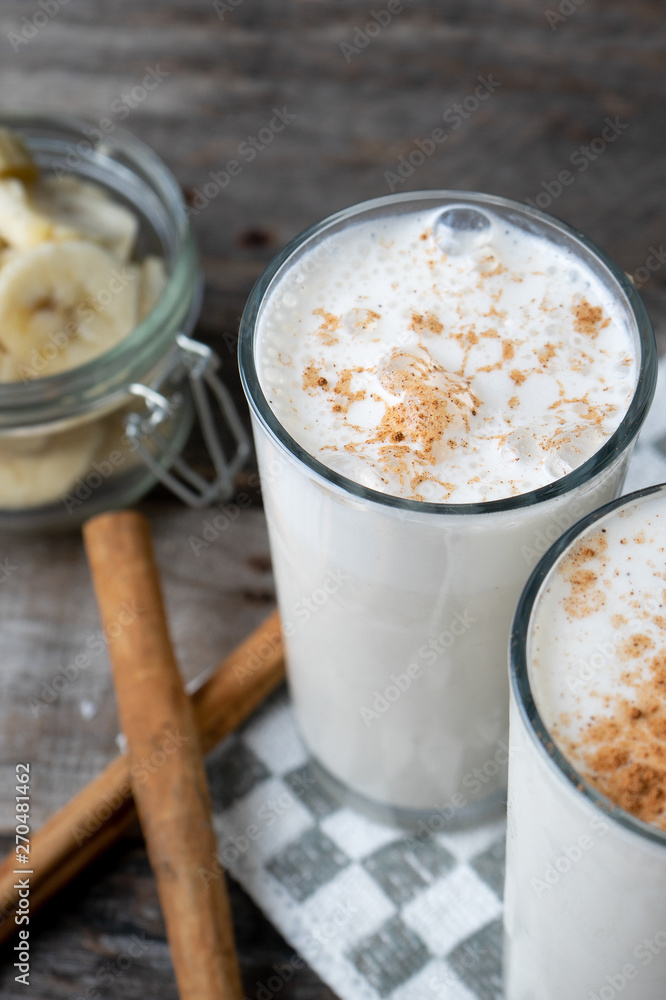 Banana smothie or milkshake with cinnamon on wood background Banana smothie or milkshake with cinnamon on wood background