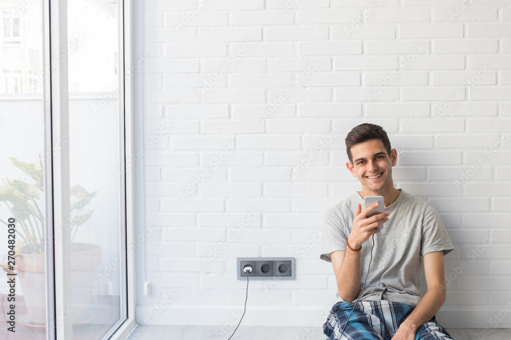 young man with mobile phone at home in the morning young man with mobile phone at home in the morning