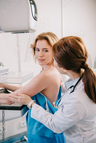 Foto young doctor assisting patient while making mammography test on x-ray machine