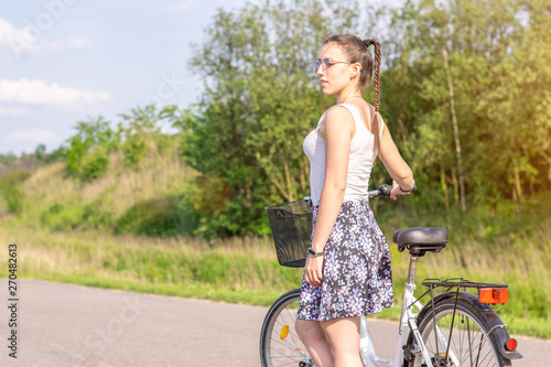 Active life. A woman with a bike enjoys the view at summer forest. Bicycle and ecology lifestyle concept.