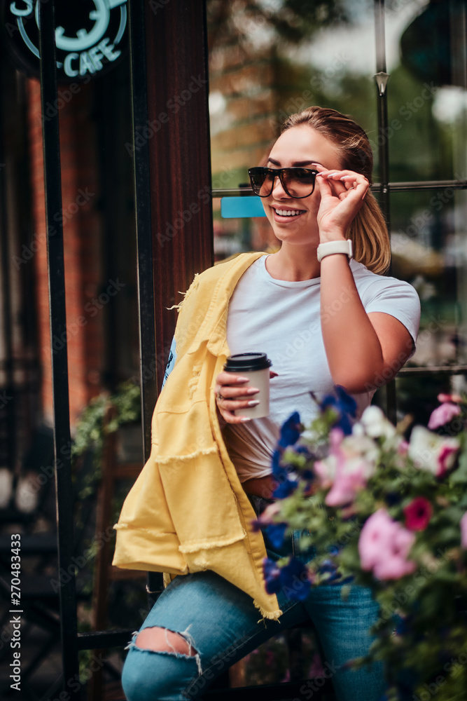 Young attractive woman with takeaway cup of coffee is enjoying summer outside.