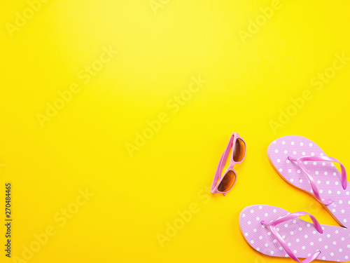 Summer flat lay. Beach accessories pink flip flops and sunglasses on yellow background. Summer trevel and vacation concept