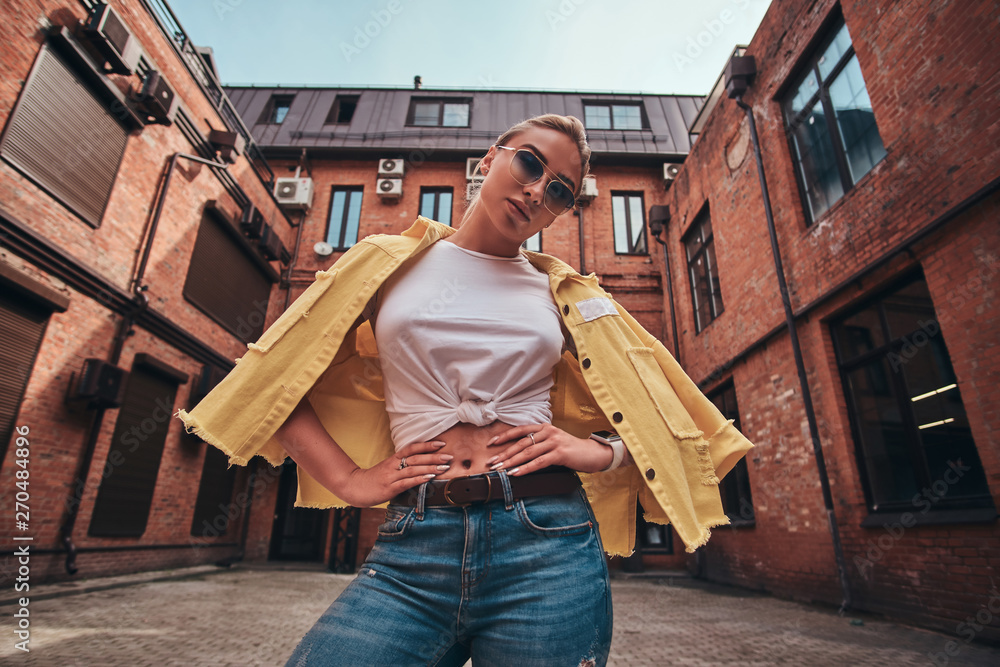Φωτογραφία Low angle photo of casual pretty woman in sunglasses and denim at symmetric yard