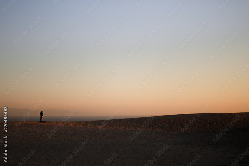 Alone man on the beach with silhouette of a dune