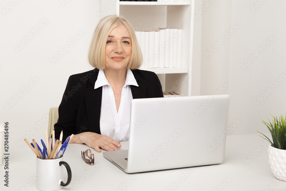 Happy woman in office sitting and working at her desk on the computer Happy woman in office sitting and working at her desk on the computer