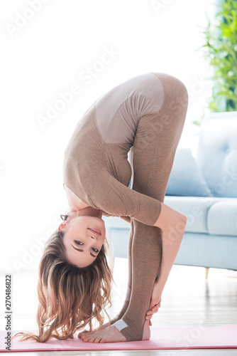 Young fitness beautiful woman female doing sport exercise and yoga workout on yoga mat in morning. Healthy lifestyle, morning workout concept