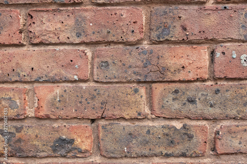 Red brick wall with holes and grime