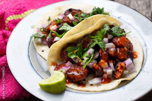 Mexican food: Delicious red chorizo tacos on wooden background