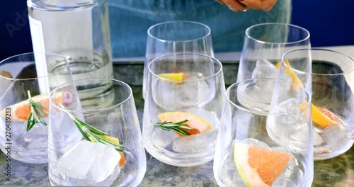 Woman hands garnishing cocktails with rosemary and grapefruit slices