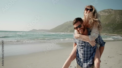 Loving couple having fun on beach piggy-back ride