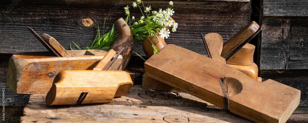 Antique hand tools, a group of planes. Wildflowers and carpentry tools. Panoramic photo. Antique hand tools, a group of planes. Wildflowers and carpentry tools. Panoramic photo.
