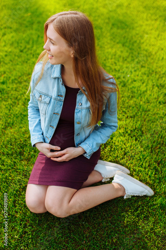 Happy young pregnant woman sitting in the park on the lawn, © Shopping King Louie