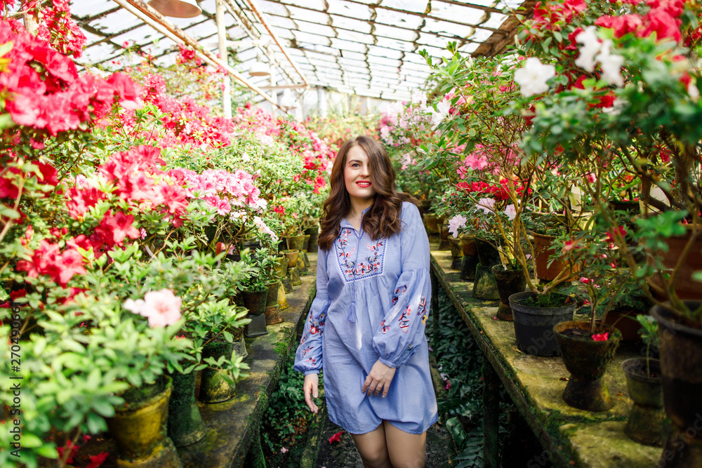portrait of a young beautiful woman in a blue dress in a beautiful botanic garden with flowers portrait of a young beautiful woman in a blue dress in a beautiful botanic garden with flowers