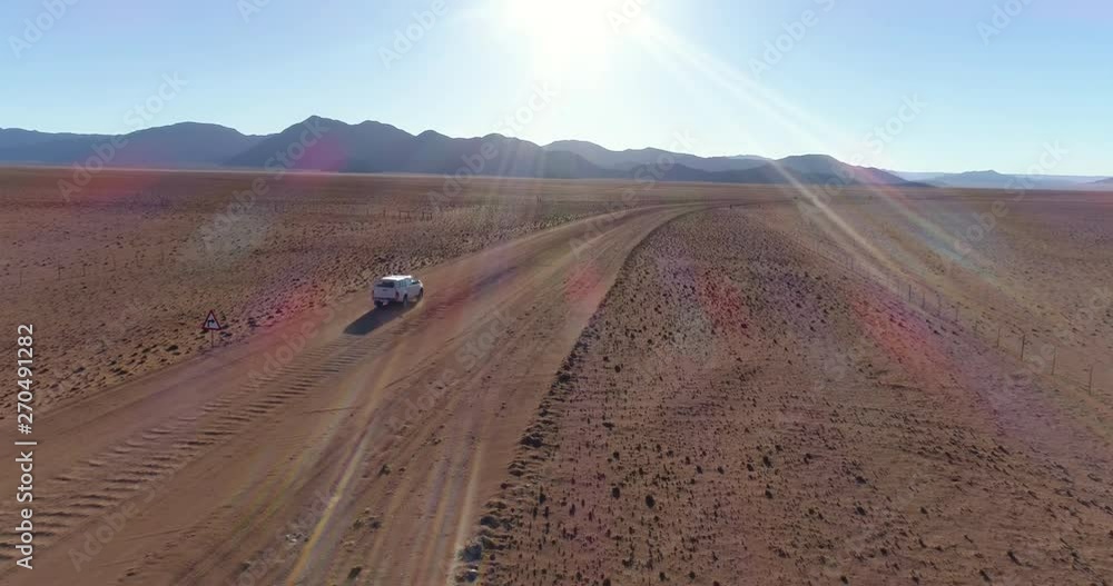 Aerial view of tourist vehicle driving on gravel road in the desert of Namibia Aerial view of tourist vehicle driving on gravel road in the desert of Namibia