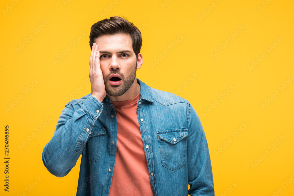 shocked handsome man touching face and looking at camera Isolated On yellow shocked handsome man touching face and looking at camera Isolated On yellow