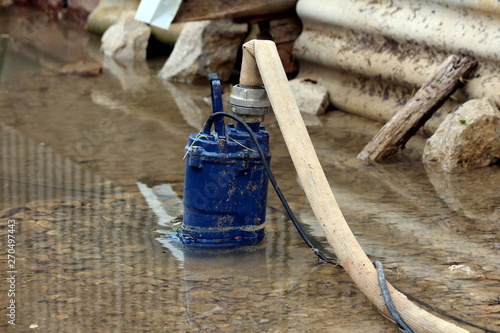 Fotografie Heavily used old partially submerged metal water pump pumping water from flooded
