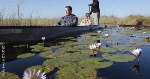 Close-up of tourists enjoying a ride on a Mokoro at sunset - traditional canoe in the Okavango Delta photo