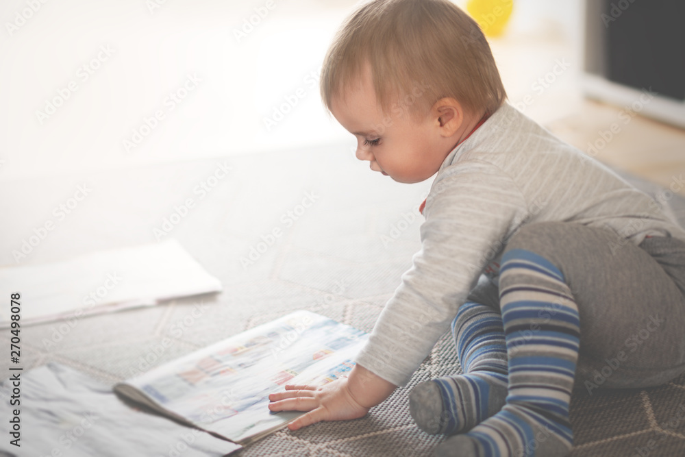 Small boy is sitting on floor and reading magazines, shallow focus Small boy is sitting on floor and reading magazines, shallow focus
