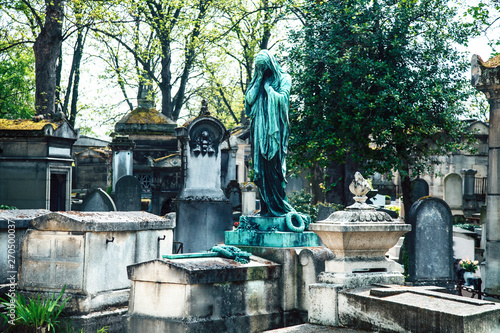 Tombstones in cemetery at dusk, gothic style crosses Paris