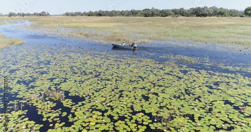 Aerial view of a tourist boat making its way through the water lillies on one of the many curving waterways of the Okavango Delta photo