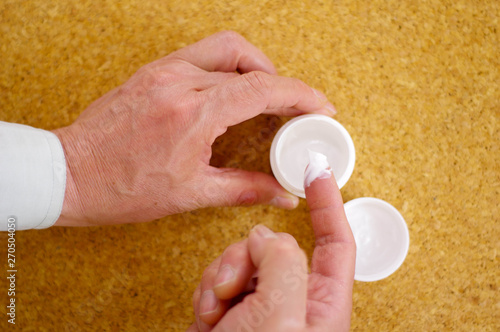 白い美容クリームの容器を開ける