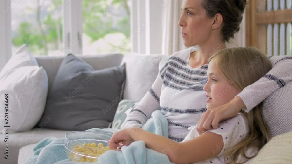 smiling mother and daughter watching movies and eating popcorn smiling mother and daughter watching movies and eating popcorn