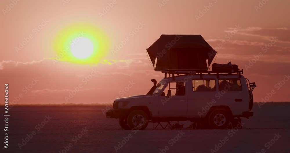 Time-lapse of a 4x4 tourist vehicle and the sun setting in the Makgadikgadi Pans,Botswana Time-lapse of a 4x4 tourist vehicle and the sun setting in the Makgadikgadi Pans,Botswana