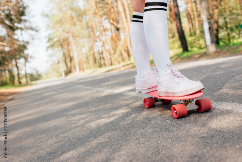 partial view of girl in knee socks skateboarding on road