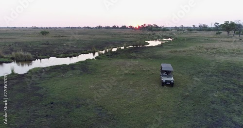 Aerial scenic view of a tourist 4x4 vehicle parked next to one of the many waterways of the Okavango Delta, Botswana photo