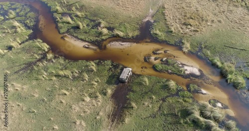 Aerial scenic view of a tourist 4x4 vehicle crossing one of the many waterways of the Okavango Delta, Botswana photo