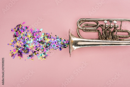 colorful confetti with trumpet on pink background