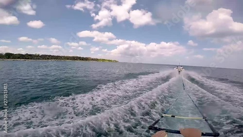 Gopro head shot on monoskier being pulled along by watersking boat. Sunny skies with blue waters. Skier crosses wake and goes round corner. photo