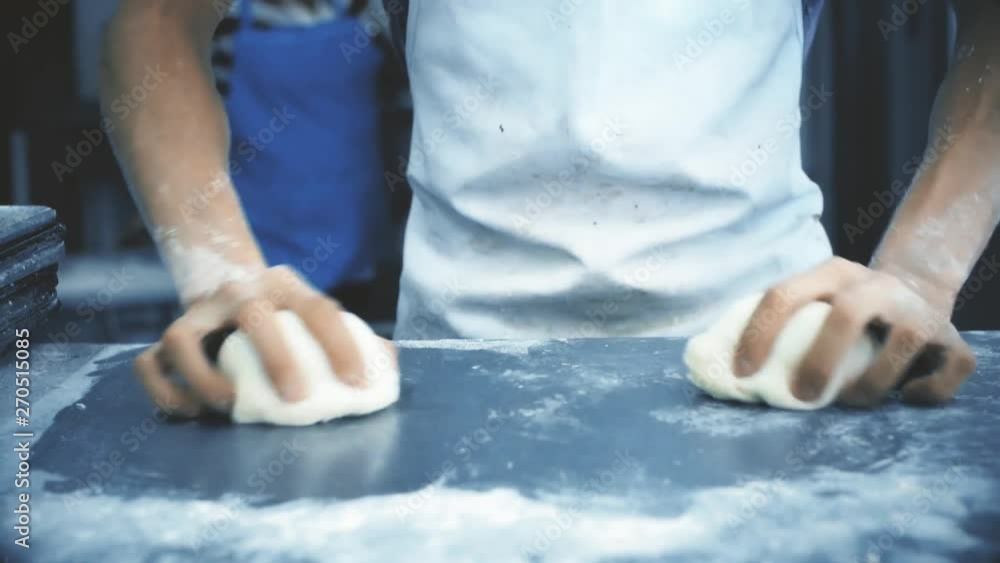 Male hands kneading the dough for bread on a table sprinkled with flour Male hands kneading the dough for bread on a table sprinkled with flour