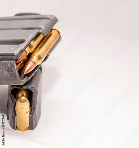 A loaded 223 rifle magazine on top of a loaded 9mm pistol magazine on a white background