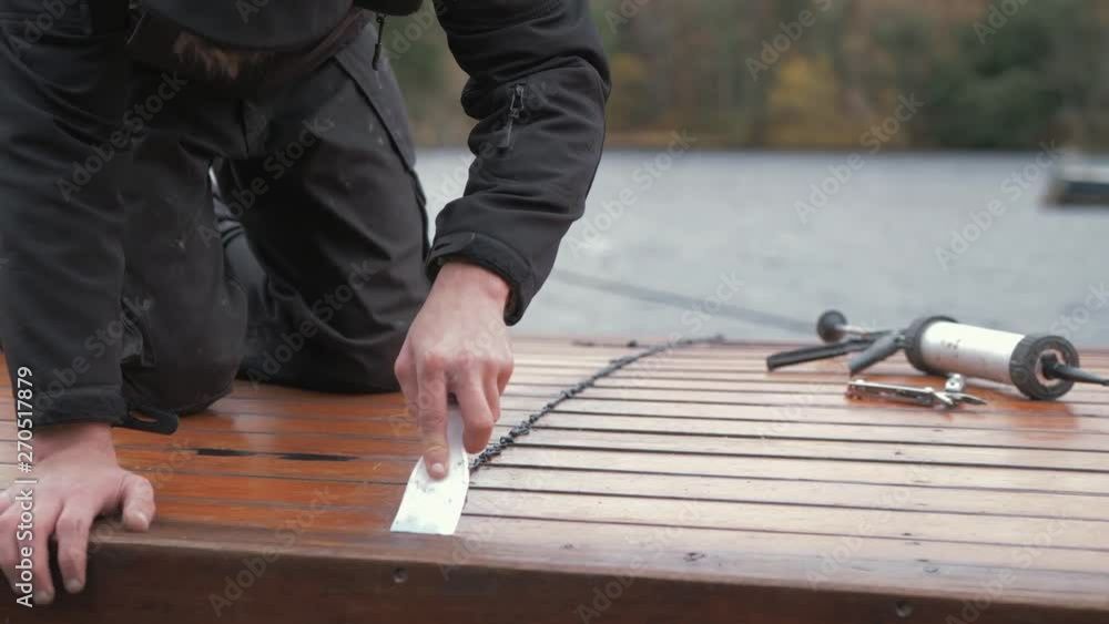 Carpenter repairing cabin roof of boat sealing leaks flattening mastic