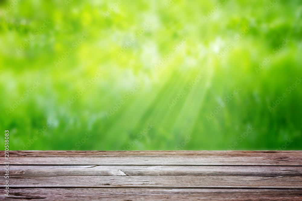 Wooden table on a background of blurred green grass with sun rays. Template, element for advertising Wooden table on a background of blurred green grass with sun rays. Template, element for advertising