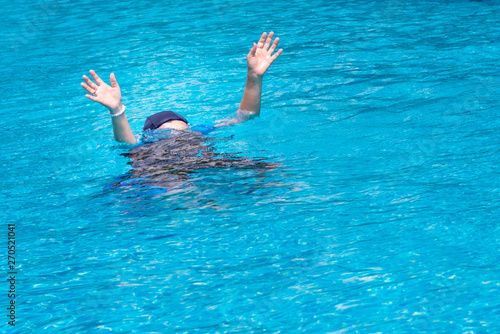 Woman are raising their hands for help, because they are weak, and is drowning while he swims in the pool, to sport and recreation concept.