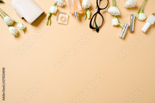 Female workspace with glasses, roses flowers, perfume bottle, golden accessories on white background. Flat lay women's office desk. Top view feminine background. Fashion blogger workplace concept.