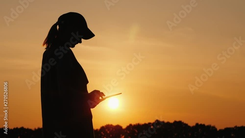 The power of the agronomist uses digital tablet outdoors in a beautiful place at sunset photo