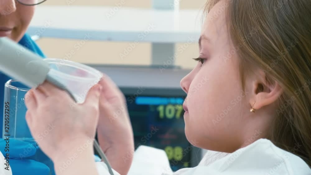 Close up shot of kid with biosensor on finger taking pill with water from nurse's hand in sickroom Close up shot of kid with biosensor on finger taking pill with water from nurse's hand in sickroom