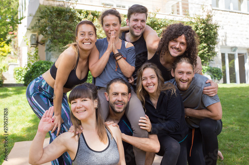 Happy yoga team posing outdoors. Men and women in fitness apparels standing for camera, laughing, and having fun. Healthy lifestyle or outdoor activity concept