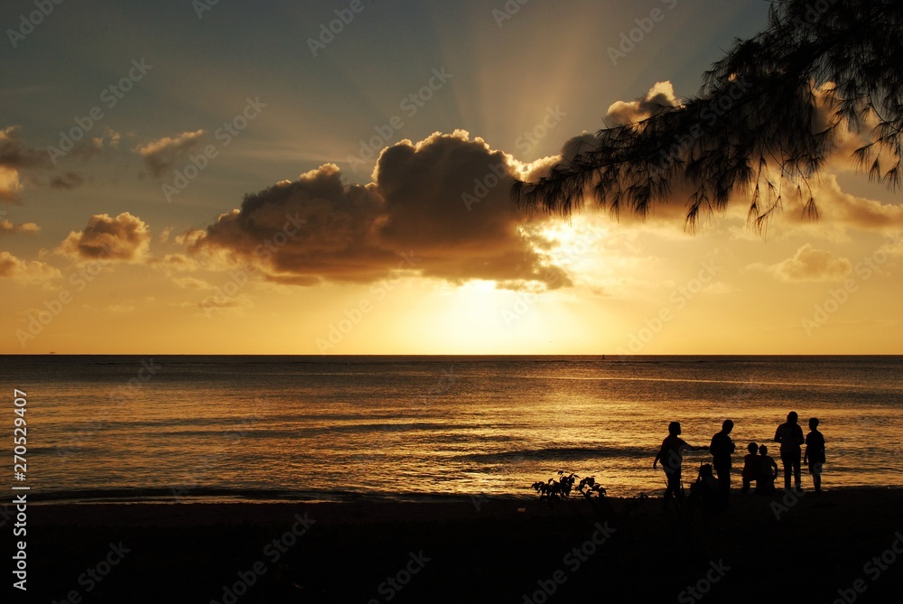 Gorgeous clouds and silhouettes of people on the beach at sunset