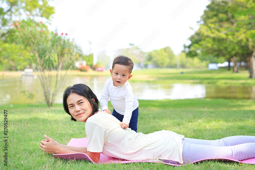 Happy family Asian mom and her son lying on green lawn background. Happy family Asian mom and her son lying on green lawn background.