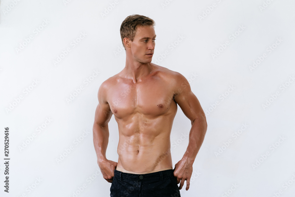 Portrait of sexy athletic man with naked torso poses on white background.