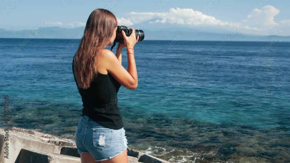 Side view of girl tourist photographer takes pictures of ocean and mountains. Side view of girl tourist photographer takes pictures of ocean and mountains.