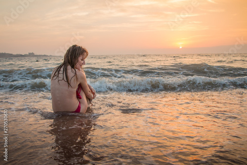 Girl rests and has fun in sea wave at sunset