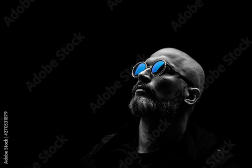 Bald man with grey beard in sunglass on dark background